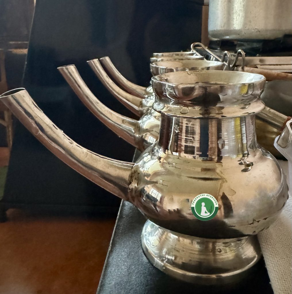 Four metal vessels are placed in a row. They are called kindi and are used in Ayurvedic pouring treatments.